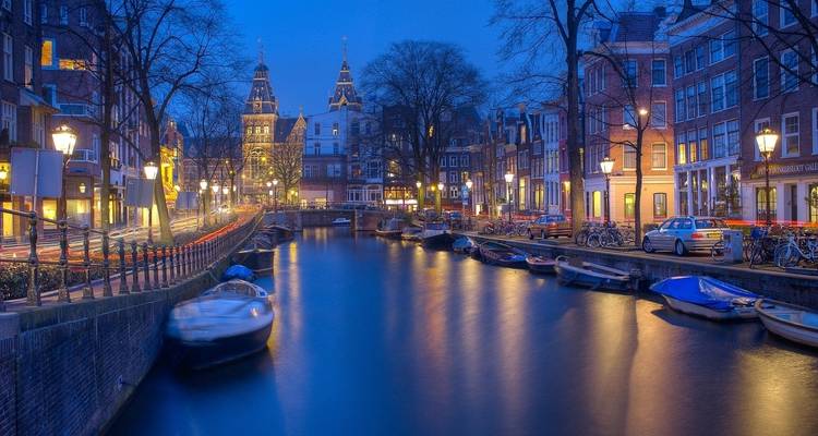 Hermosa escena nocturna de canal con edificios y barcos iluminados