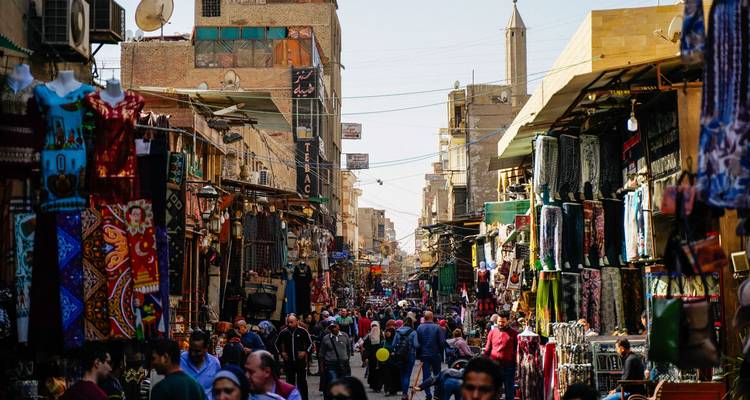 Calle de mercado concurrida con numerosos puestos que venden diversos productos.