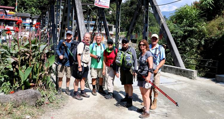 Grupo de excursionistas parados en un puente en una región montañosa.