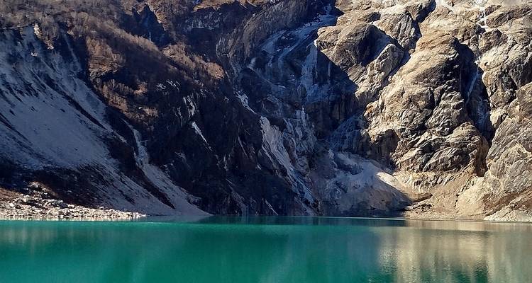 Lago alpino de color turquesa rodeado de empinadas laderas rocosas