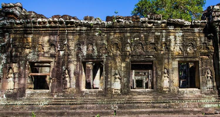 Steensnijwerk op oude tempelmuren met blauwe lucht.