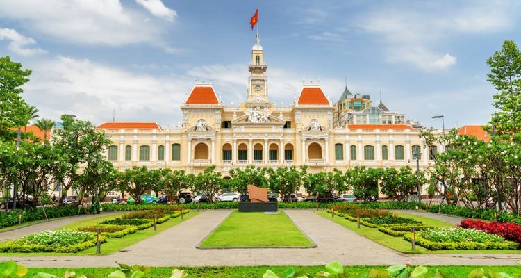 Koloniaal wit gebouw met aangelegde tuinen en rood dak.