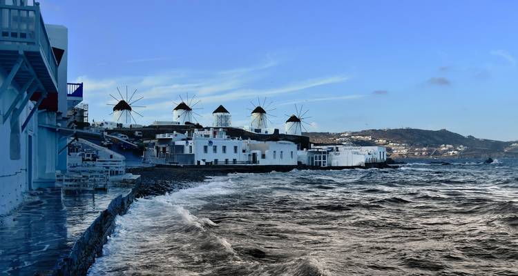 Moulins à vent emblématiques sur une colline à Mykonos, Grèce, avec un littoral.