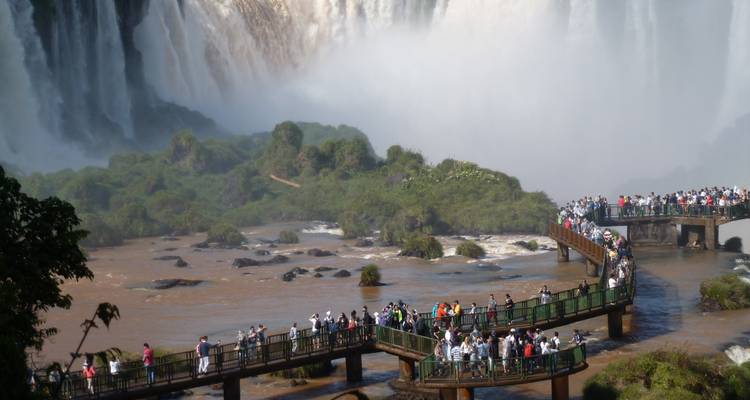 Turistas en una pasarela sobre las Cataratas del Iguazú rodeados de neblina.
