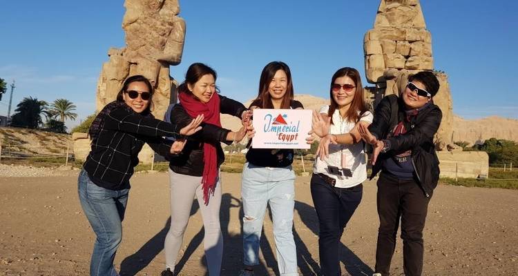 Groupe de personnes posant avec un panneau devant des statues antiques