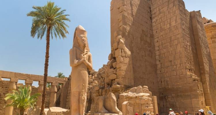 Grande statue antique avec des gens à proximité