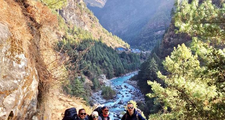 Group of hikers with a river and mountainous landscape in the background.