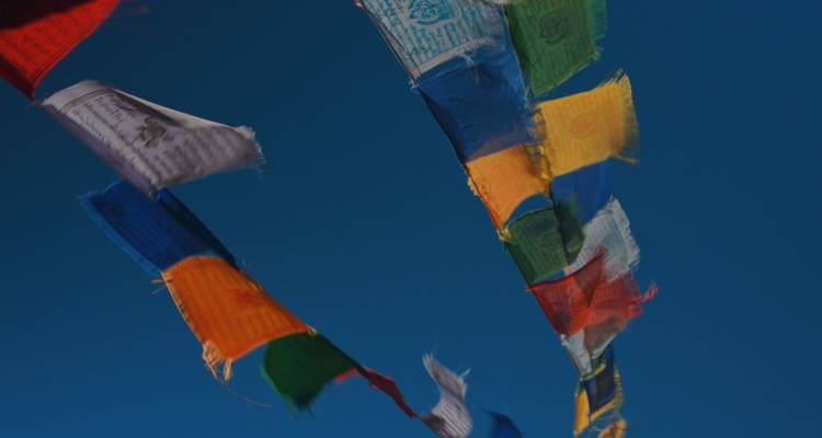 Colorful prayer flags against a clear blue sky.