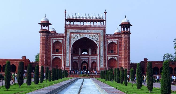 La porte d'entrée du Taj Mahal avec des visiteurs marchant à l'intérieur.
