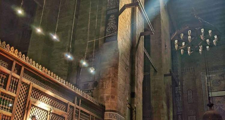 Innenraum einer Moschee mit hängenden Lichtern und detaillierter Architektur.