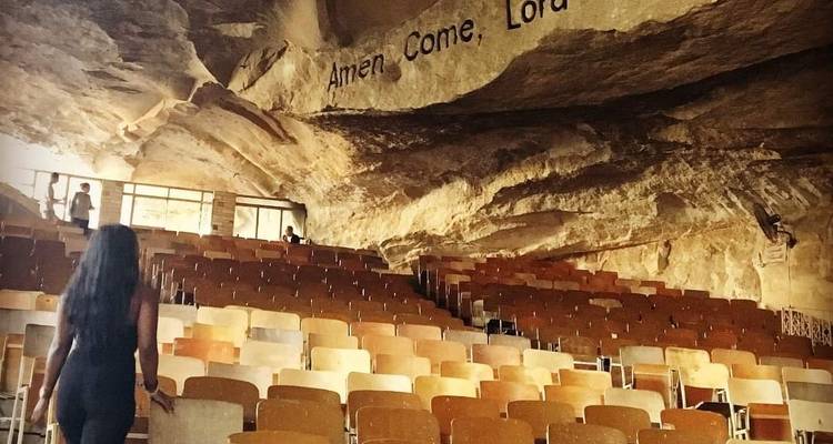 Frau, die zu einem Sitzbereich in einer Höhlenkirche mit Inschriften geht.