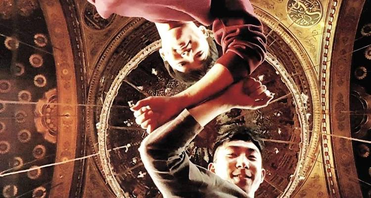 Auf dem Kopf stehendes Foto von zwei Personen, die unter einer dekorativen Kuppel posieren.