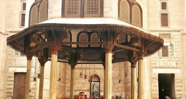 Person unter einem historischen Baldachin in einem Innenhof.