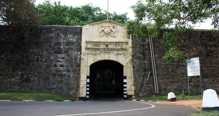 Historischer Festungseingang mit gravierten Steinen und Bäumen.