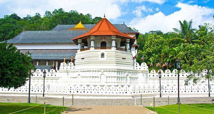 Weiße Tempelstruktur mit einem roten Dach, umgeben von Flaggen.