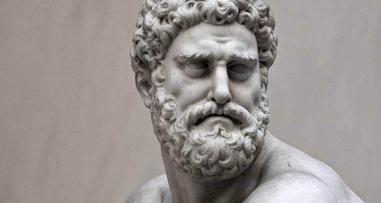 Primer plano del rostro barbudo y expresivo de una estatua de mármol clásica bajo la suave iluminación del museo.
