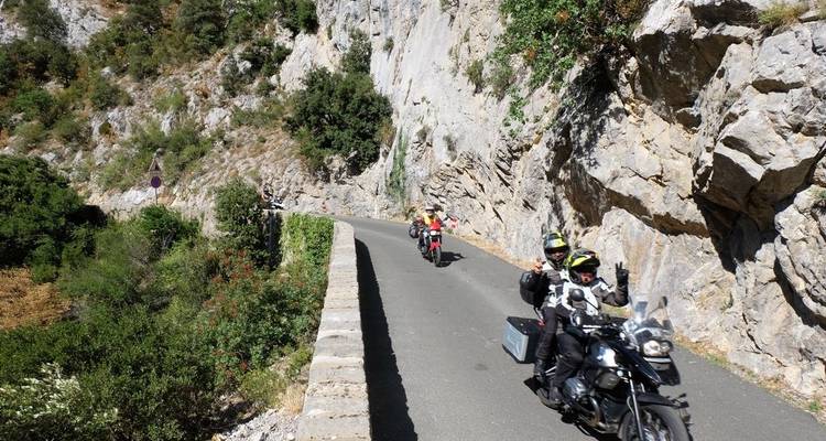 Motorradfahrer, die durch einen schmalen Gebirgspass mit steilen Klippen fahren.