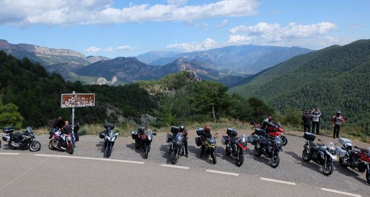 Gruppe von Motorrädern, die auf einer malerischen Bergstraße geparkt sind.