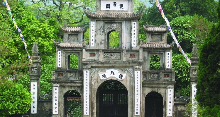 Een oude sierlijke stenen poort omgeven door weelderig groen.