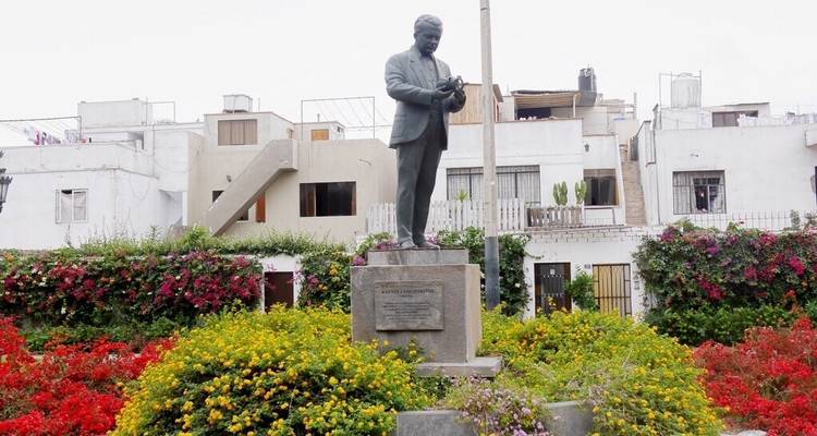 Garten mit einer Statue, umgeben von bunten Blumen und Wohngebäuden.