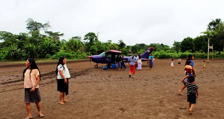 Gente caminando desde una pequeña aeronave en una pista de aterrizaje rural.