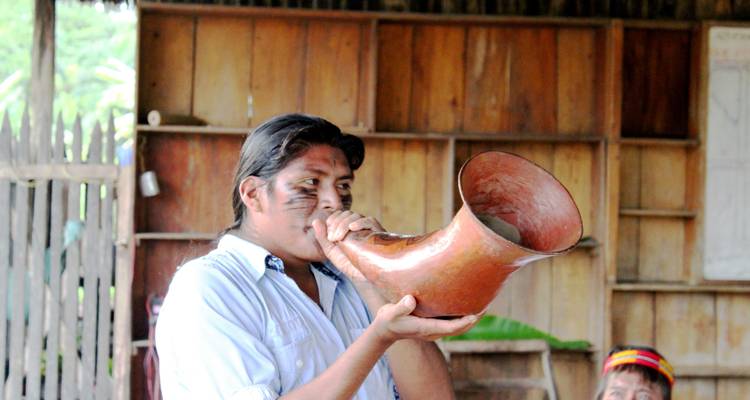 Hombre soplando en un cuerno grande en una estructura de madera.