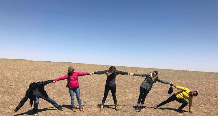 Grupo de personas tomadas de la mano en una fila en un paisaje desértico.