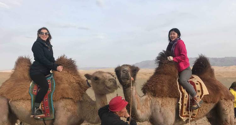 Dos personas montando camellos en un paisaje desértico.