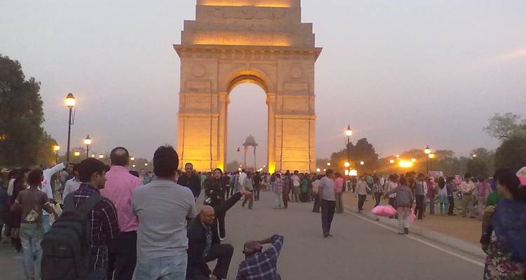 Zona concurrida alrededor de la Puerta de la India, un monumento iluminado.