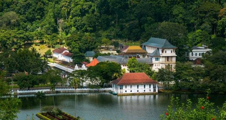 Temple of the Tooth complex beside tranquil lake surrounded by lush greenery