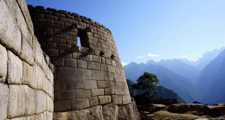 Structure de pierre ancienne avec un décor montagneux en arrière-plan, probablement le Machu Picchu.