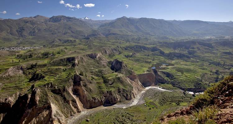 Un paisaje amplio y accidentado con colinas aterrazadas y un río.