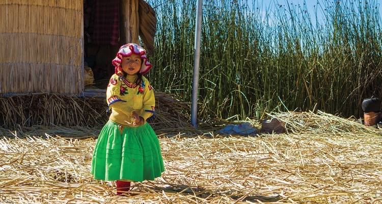 Kind in traditioneller Kleidung steht auf Schilf.