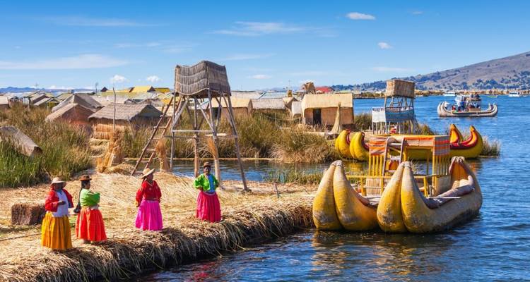 Traditionelle Boote und Menschen in bunten Kleidern in der Nähe von Schilfinseln.