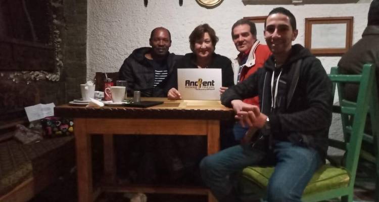 Group of people sitting around a table inside holding a sign.