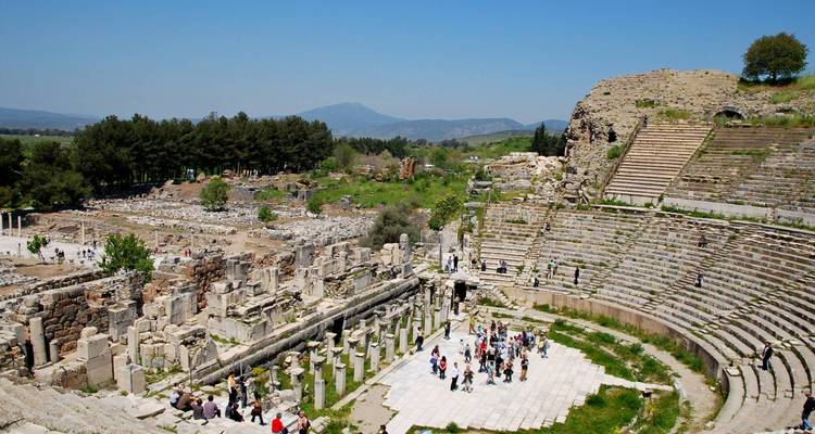 Ruinas antiguas de un anfiteatro con turistas explorando.
