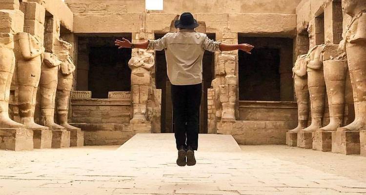 Persoon die leviteert in een historische tempel met grote standbeelden.