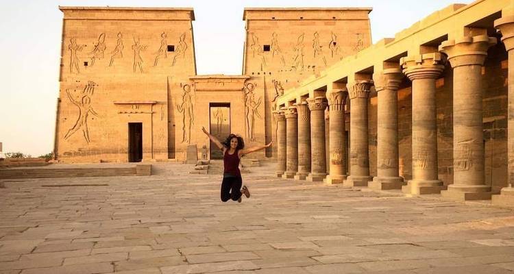 Frau springt vor dem Philae-Tempel.