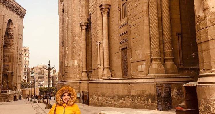 Frau, die vor einer großen, alten Moschee steht.