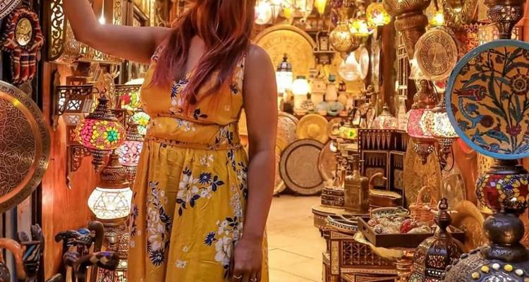 Frau erkundet einen Basar voller bunter Lampen.