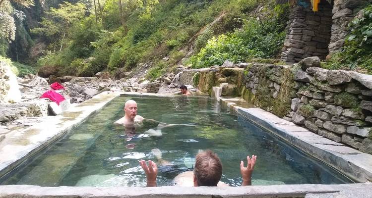 Mensen die ontspannen in een natuurlijke warmwaterbron omgeven door de natuur.