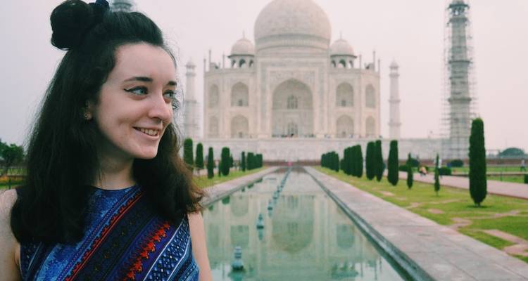 Gros plan d'une femme souriante avec le Taj Mahal en arrière-plan.