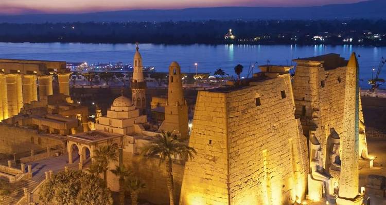 Aerial view of an ancient Egyptian temple by the river at dusk.