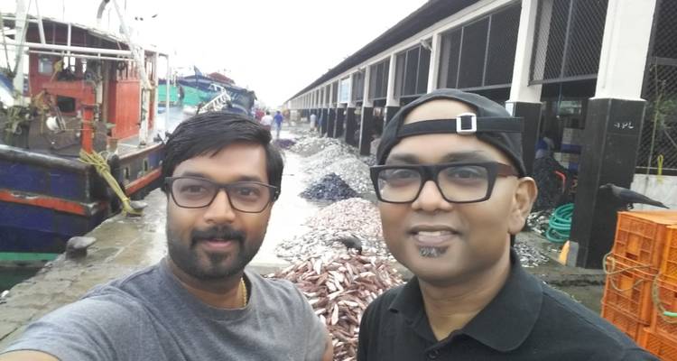 Zwei Menschen auf einem lebhaften Fischmarkt mit Booten.