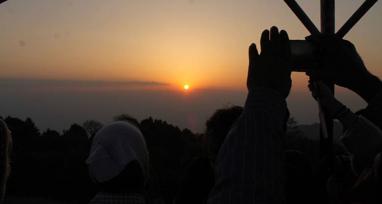 Silueta de personas tomando fotos de una puesta de sol.