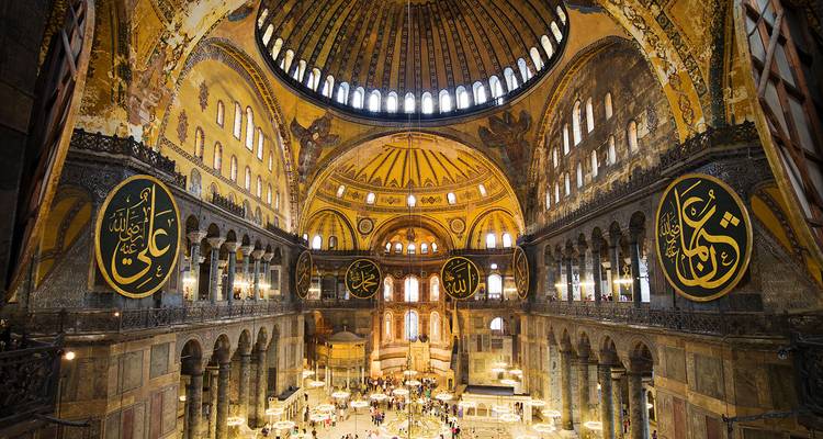 Prachtvolles Inneres der Hagia Sophia mit goldenen Kuppeln, islamischen Kalligraphie-Medaillons und Besuchern darunter.