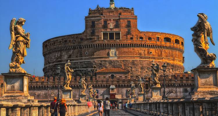 Vue en direction du Pont Sant'Angelo vers le Château Sant'Angelo, flanqué de statues d'anges sous un ciel bleu.