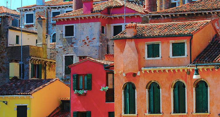 Façades colorées de vieilles maisons vénitiennes avec de la peinture écaillée et des volets verts.