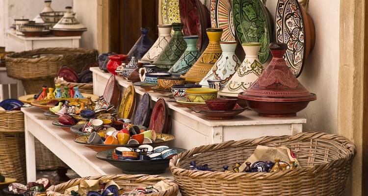 Une collection de pots et plats en céramique colorés exposés sur une table.