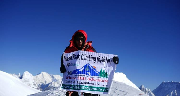 Klimmer op de top met een bord voor Mera Peak.
